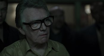 Movie still from “Snatch” (2000), directed by Guy Ritchie – An older man wearing glasses looking at the camera; Close Up shot, Over the shoulder angle
