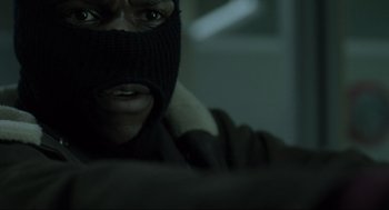 Movie still from “Snatch” (2000), directed by Guy Ritchie – A man wearing a black balaclava and a black jacket; Close Up shot, Overhead angle