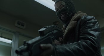 Movie still from “Snatch” (2000), directed by Guy Ritchie – A man with a gun wearing a balaclava and a mask; Medium shot, Low angle