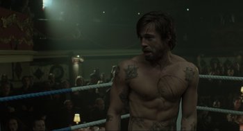 Movie still from “Snatch” (2000), directed by Guy Ritchie – A man in a boxing ring with a tattoo on his chest; Medium shot, Over the shoulder angle