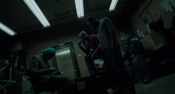 Movie still from “Snatch” (2000), directed by Guy Ritchie – A group of people sitting in a dark room; Wide shot, High angle