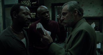 Movie still from “Snatch” (2000), directed by Guy Ritchie – A group of men standing next to each other holding papers; Medium shot, Over the shoulder angle