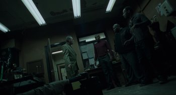 Movie still from “Snatch” (2000), directed by Guy Ritchie – A group of men standing around in a room; Wide shot, High angle
