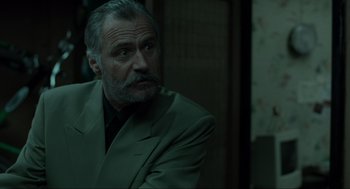 Movie still from “Snatch” (2000), directed by Guy Ritchie – An older man in a green suit looking to his left; Close Up shot, Over the shoulder angle