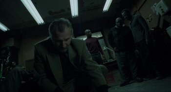 Movie still from “Snatch” (2000), directed by Guy Ritchie – A group of men standing in a dark room; Medium shot, Low angle