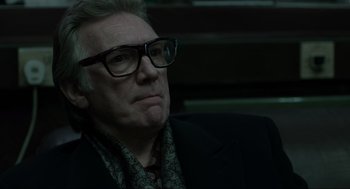 Movie still from “Snatch” (2000), directed by Guy Ritchie – An older man wearing glasses and a suit; Close Up shot, Over the shoulder angle