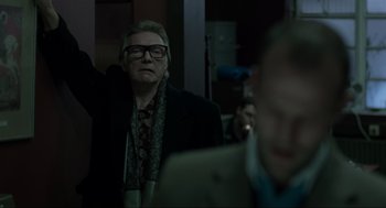 Movie still from “Snatch” (2000), directed by Guy Ritchie – An older man wearing glasses and a black jacket; Medium shot, Low angle