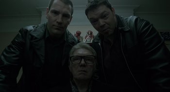 Movie still from “Snatch” (2000), directed by Guy Ritchie – A group of men standing next to each other in a room; Medium shot, Low angle