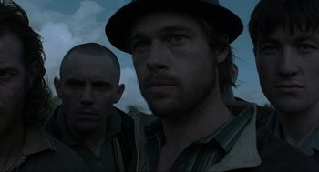 Movie still from “Snatch” (2000), directed by Guy Ritchie – A man with a hat is standing next to another man; Close Up shot, Low angle