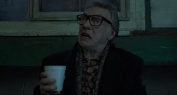 Movie still from “Snatch” (2000), directed by Guy Ritchie – An older man with glasses holding a cup of coffee; Close Up shot, Low angle