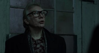 Movie still from “Snatch” (2000), directed by Guy Ritchie – An older man wearing glasses and a black jacket; Close Up shot, Over the shoulder angle