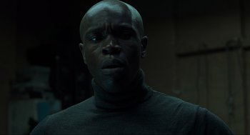 Movie still from “Snatch” (2000), directed by Guy Ritchie – A man with a black shirt is looking at the camera; Close Up shot, Low angle