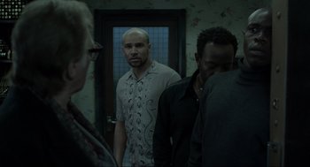 Movie still from “Snatch” (2000), directed by Guy Ritchie – A group of people standing in a room; Medium shot, Over the shoulder angle