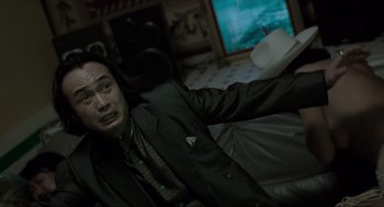 Movie still from “Snatch” (2000), directed by Guy Ritchie – A man sitting on a couch in a living room; Close Up shot, Low angle