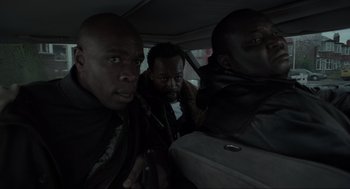 Movie still from “Snatch” (2000), directed by Guy Ritchie – A group of people in a car looking at the camera; Close Up shot, Low angle