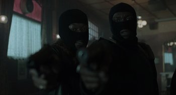 Movie still from “Snatch” (2000), directed by Guy Ritchie – Two men in balaclavas are holding guns in a room; Close Up shot, Low angle