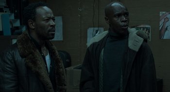 Movie still from “Snatch” (2000), directed by Guy Ritchie – Two men standing next to each other in a dark room; Medium shot, Low angle