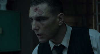 Movie still from “Snatch” (2000), directed by Guy Ritchie – A person wearing a suit and tie; Close Up shot, Low angle