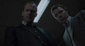 Movie still from “Snatch” (2000), directed by Guy Ritchie – Two men standing next to each other in front of a light; Close Up shot, Low angle