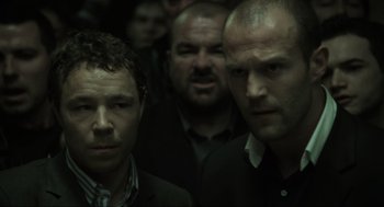 Movie still from “Snatch” (2000), directed by Guy Ritchie – A group of men standing next to each other in a room; Close Up shot, Low angle