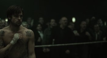 Movie still from “Snatch” (2000), directed by Guy Ritchie – A crowd of people in a boxing ring watching; Close Up shot, Over the shoulder angle