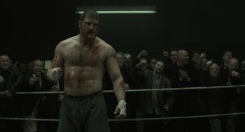 Movie still from “Snatch” (2000), directed by Guy Ritchie – A man in a boxing ring with blood all over his face; Medium shot, Low angle