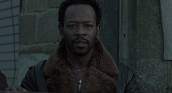 Movie still from “Snatch” (2000), directed by Guy Ritchie – A man wearing a leather jacket with a cross on it; Close Up shot, Low angle