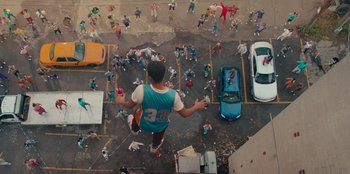 Movie still from “Sneakerella” (2022), directed by Elizabeth Allen Rosenbaum – An aerial view of a man standing in the middle of a parking lot; Wide shot, Overhead angle