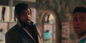 Movie still from “Sneakerella” (2022), directed by Elizabeth Allen Rosenbaum – A man with a beard is standing in a room; Close Up shot, Over the shoulder angle