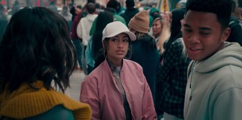 Movie still from “Sneakerella” (2022), directed by Elizabeth Allen Rosenbaum – A woman wearing a baseball cap standing in front of a group of people; Close Up shot, Over the shoulder angle