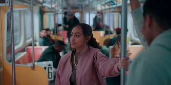 Movie still from “Sneakerella” (2022), directed by Elizabeth Allen Rosenbaum – A woman in a pink jacket is on a bus; Medium shot, Over the shoulder angle