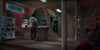Movie still from “Sneakerella” (2022), directed by Elizabeth Allen Rosenbaum – Three men are standing in a room near a stair case; Wide shot, Low angle
