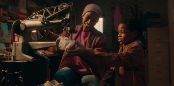 Movie still from “Sneakerella” (2022), directed by Elizabeth Allen Rosenbaum – A woman and a child are playing a video game together; Close Up shot, Low angle