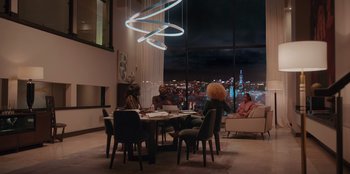 Movie still from “Sneakerella” (2022), directed by Elizabeth Allen Rosenbaum – A group of people sitting around a table in a room; Extreme Wide shot, Low angle