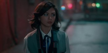 Movie still from “Sneakerella” (2022), directed by Elizabeth Allen Rosenbaum – A young woman in a vest and tie standing on the street; Close Up shot, Over the shoulder angle