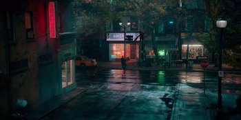 Movie still from “Sneakerella” (2022), directed by Elizabeth Allen Rosenbaum – A person is walking down the street in the rain; Extreme Wide shot, High angle