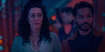 Movie still from “Sneakerella” (2022), directed by Elizabeth Allen Rosenbaum – A woman standing next to a man in front of a crowd; Close Up shot, Over the shoulder angle