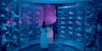 Movie still from “Sneakerella” (2022), directed by Elizabeth Allen Rosenbaum – Two people standing in front of a display of shoes; Wide shot, High angle