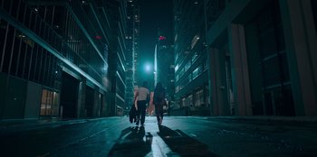 Movie still from “Sneakerella” (2022), directed by Elizabeth Allen Rosenbaum – A group of people walking down a street at night; Extreme Wide shot, Low angle