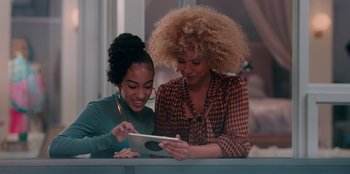 Movie still from “Sneakerella” (2022), directed by Elizabeth Allen Rosenbaum – Two women looking at an ipad in a room; Medium shot, High angle