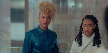 Movie still from “Sneakerella” (2022), directed by Elizabeth Allen Rosenbaum – A woman in a blue shirt with a blonde curly hair style; Close Up shot, Over the shoulder angle