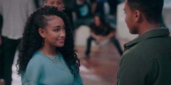 Movie still from “Sneakerella” (2022), directed by Elizabeth Allen Rosenbaum – A woman in a blue dress talking to a man in a green shirt; Medium shot, Over the shoulder angle