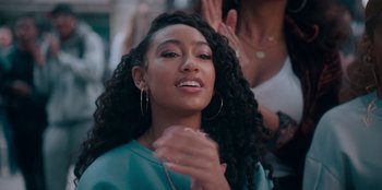 Movie still from “Sneakerella” (2022), directed by Elizabeth Allen Rosenbaum – A person with long black curly hair; Close Up shot, Over the shoulder angle