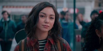Movie still from “Sneakerella” (2022), directed by Elizabeth Allen Rosenbaum – A young woman with long black hair wearing a plaid shirt; Close Up shot, Over the shoulder angle
