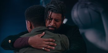 Movie still from “Sneakerella” (2022), directed by Elizabeth Allen Rosenbaum – Two men are hugging each other in the dark; Close Up shot, Over the shoulder angle