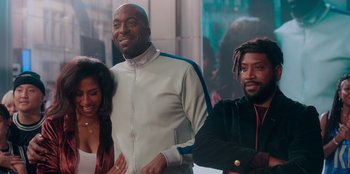 Movie still from “Sneakerella” (2022), directed by Elizabeth Allen Rosenbaum – A man standing next to two other people; Medium shot, Over the shoulder angle