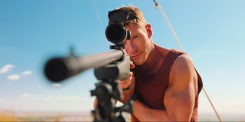 Movie still from “Sniper: G.R.I.T. - Global Response & Intelligence Team” (2023), directed by Oliver Thompson – A person holding a rifle; Close Up shot, Low angle