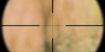 Movie still from “Sniper: G.R.I.T. - Global Response & Intelligence Team” (2023), directed by Oliver Thompson – A rifle scope with a blurry background; Extreme Close Up shot, Overhead angle