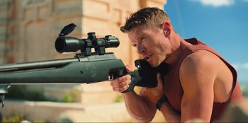 Movie still from “Sniper: G.R.I.T. - Global Response & Intelligence Team” (2023), directed by Oliver Thompson – A man is holding a rifle and aiming it; Medium shot, High angle
