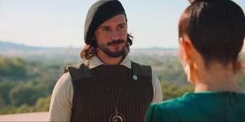 Movie still from “Sniper: G.R.I.T. - Global Response & Intelligence Team” (2023), directed by Oliver Thompson – A man with a beard wearing a hat and a sweater; Close Up shot, Over the shoulder angle